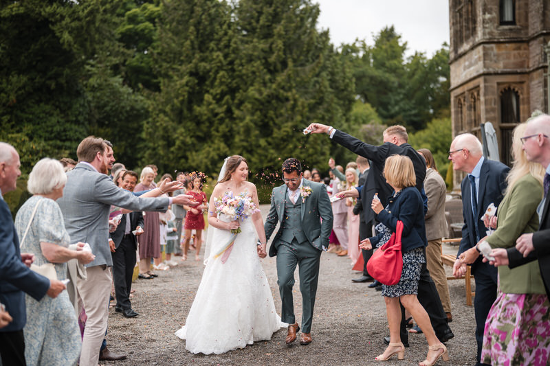 Wedding couple walking through confetti after the ceremony at Armathwaite Hall in the Lake District
