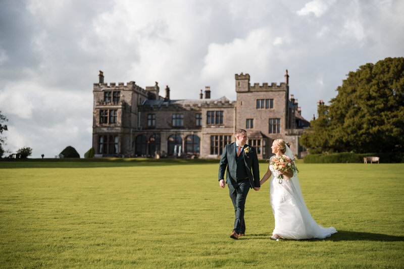 Wedding couple portrait on the lawns at Armathwaite Hall with venue backdrop in the Lake District