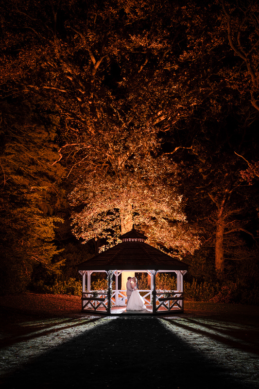 Wedding couple beneath an illuminated gazebo at Armathwaite Hall at night