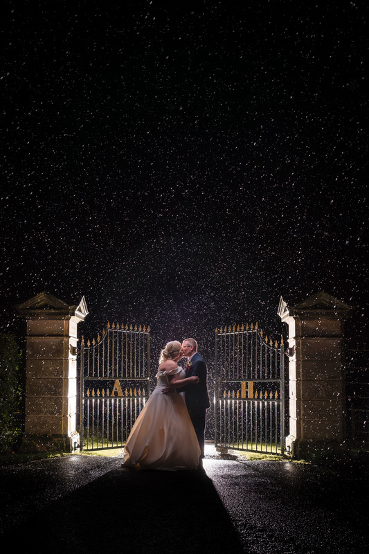 Night wedding portrait in the rain by the gates at Armathwaite Hall