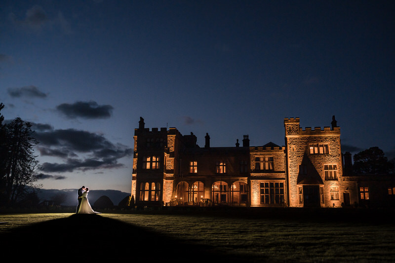 Night-time wedding couple portrait outside Armathwaite Hall with dramatic exterior lighting