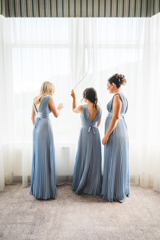 Bridesmaids by the window during wedding preparations at Inn on the Lake