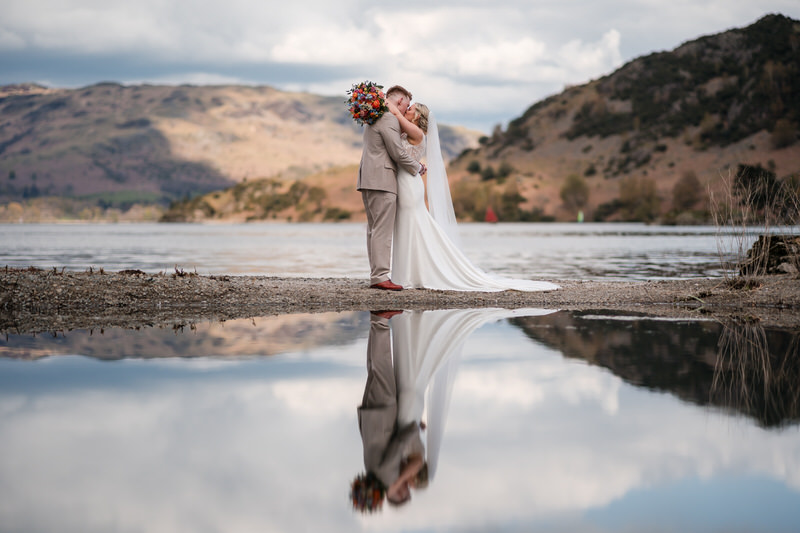 Wedding couple kiss by the lakeshore reflection at Inn on the Lake on Ullswater