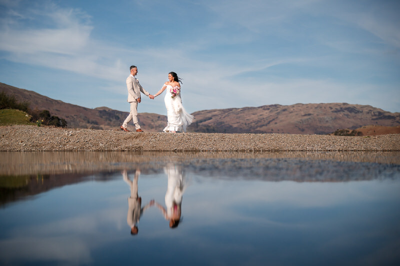 Wedding couple landscape walking with reflections at Inn on the Lake on Ullswater