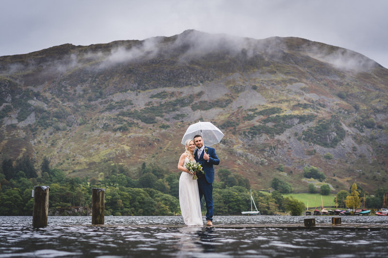 Wedding couple portrait on the Ullswater jetty with umbrella at Inn on the Lake