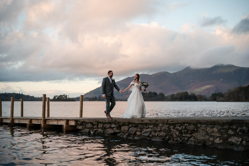 Wedding couple walking at Derwentwater jetty at sunset