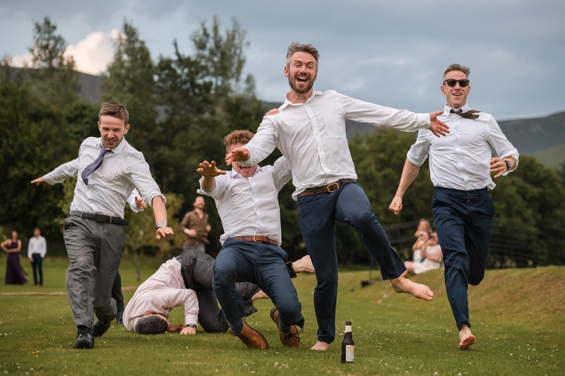 Groomsmen running during a fun wedding party moment at New House Farm