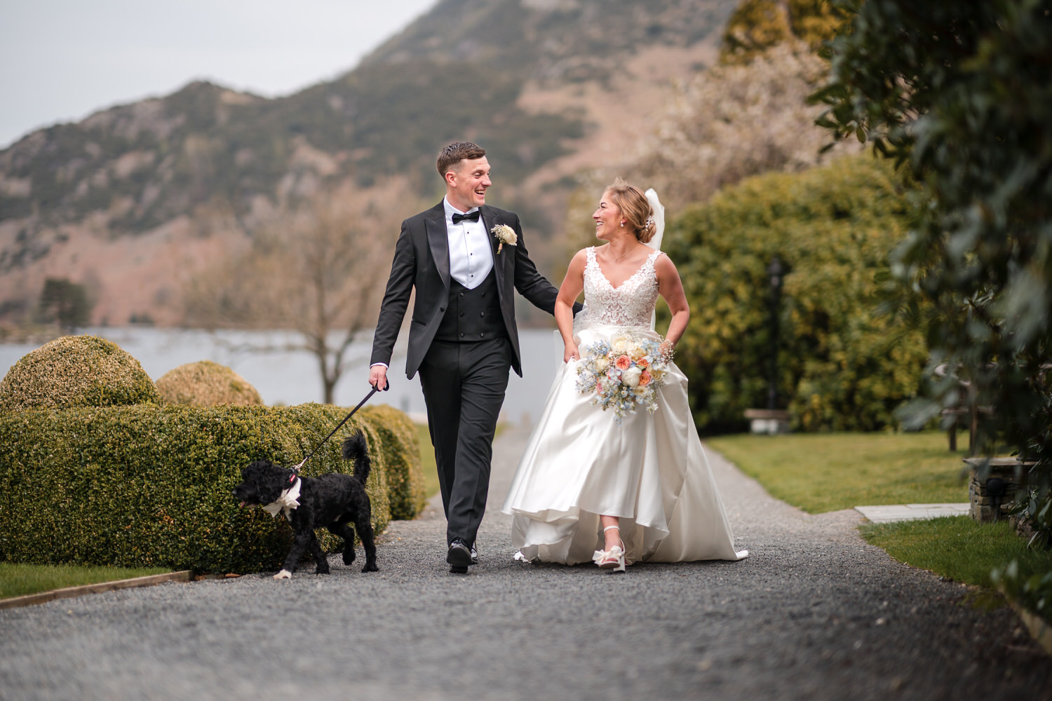 Bride and groom walking with their dog at a Lake District wedding