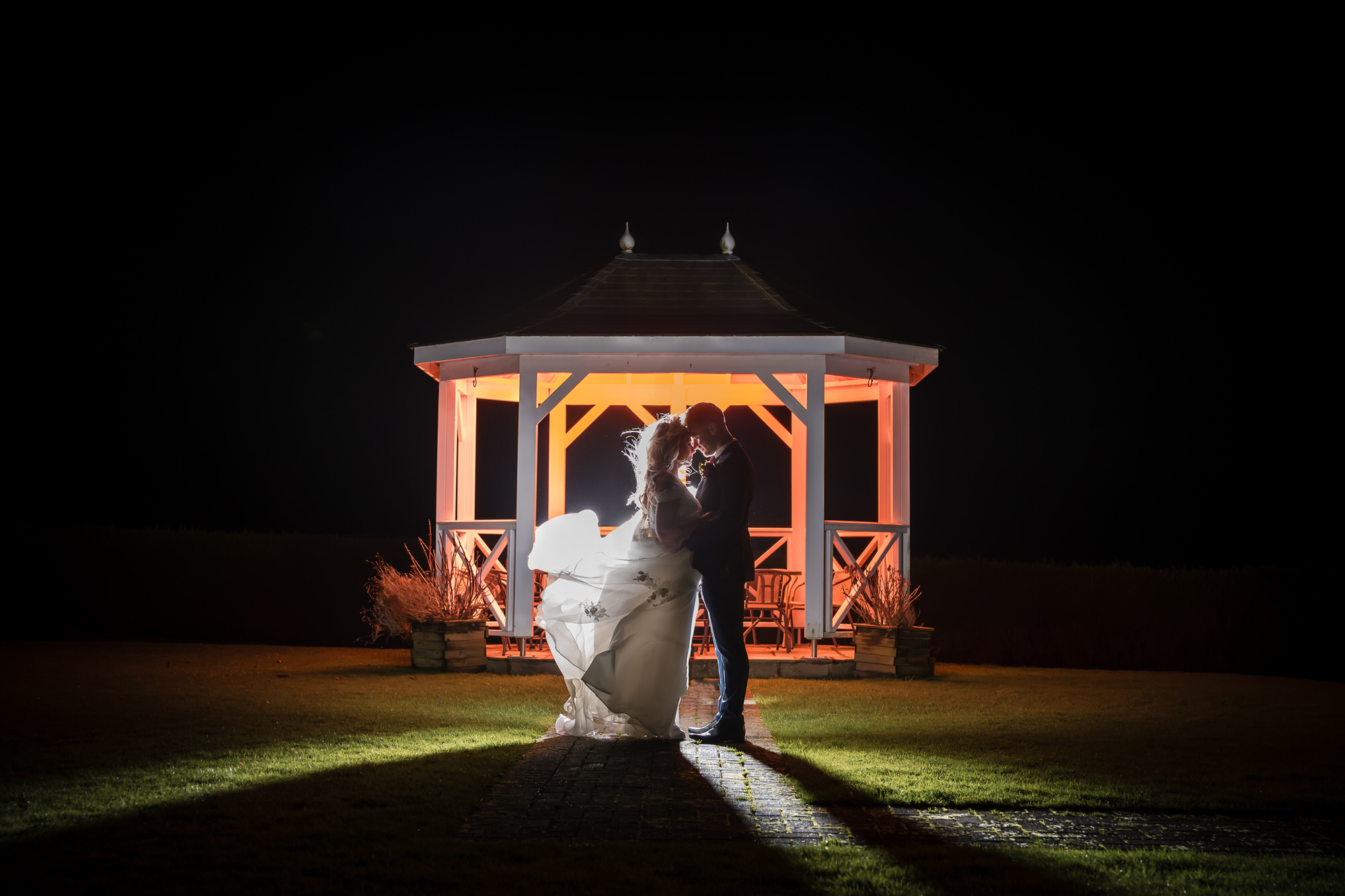 Wedding couple in front of the illuminated garden gazebo at Hundith Hill Hotel at night