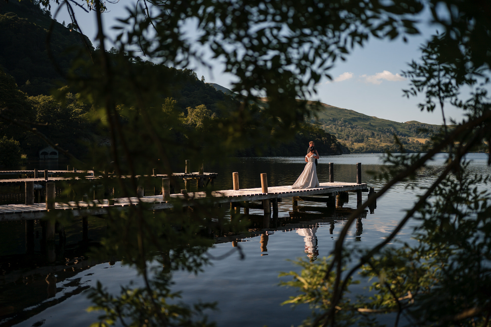 Dan and Amy together on the wooden Ullswater jetty framed through trees