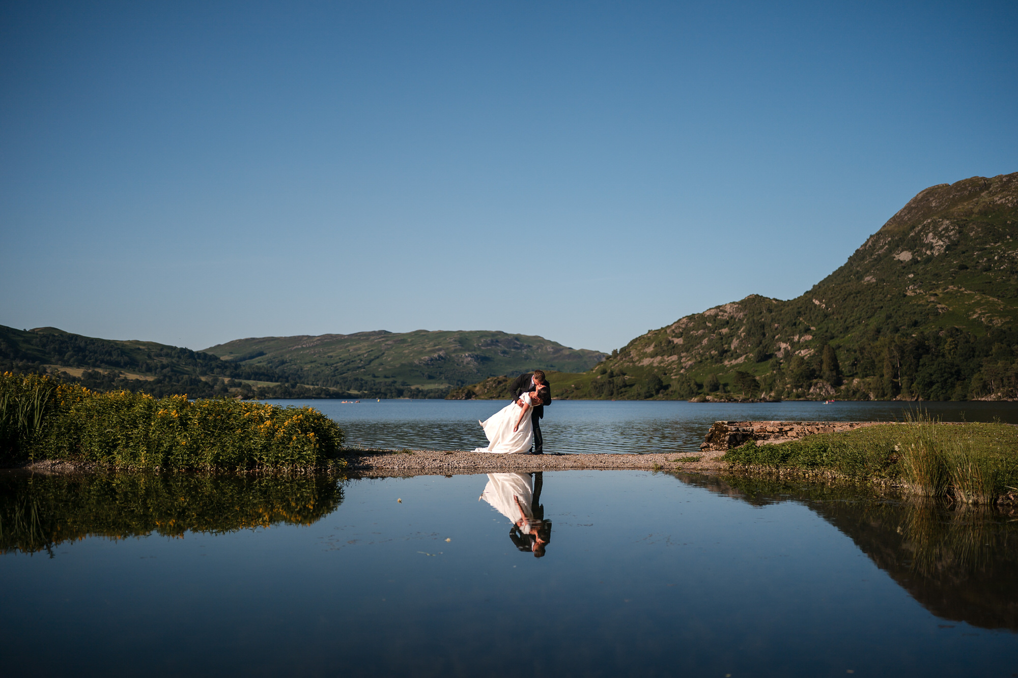 Dan dipping Amy beside Ullswater with their reflection framed by the Lake District fells