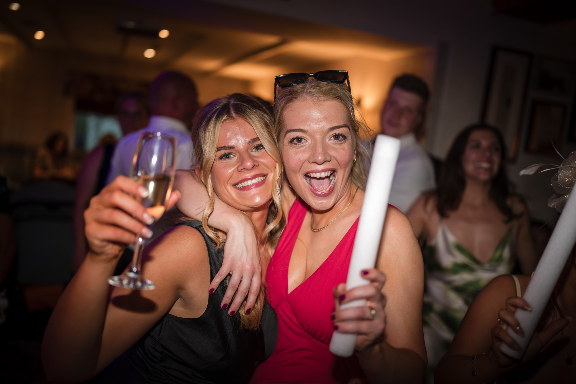 Two friends celebrating together with a drink and glow stick