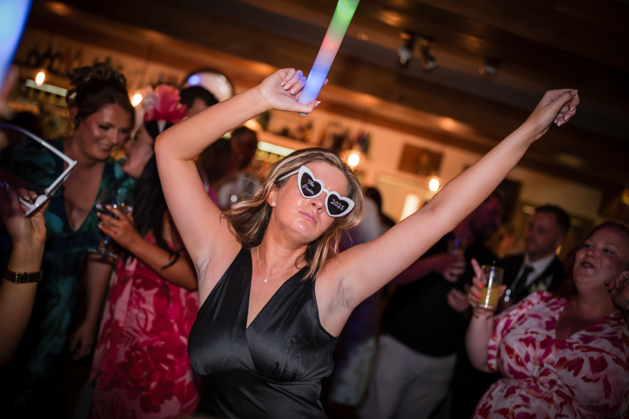 A bridesmaid dancing with a multicoloured glow stick in the Ramblers Bar