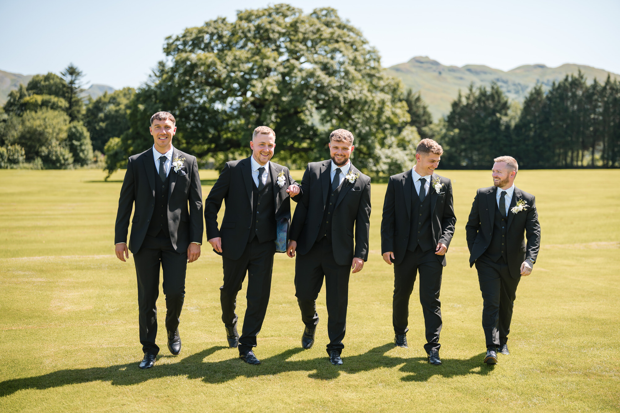 The wedding party sharing a relaxed moment in the Inn on the Lake gardens