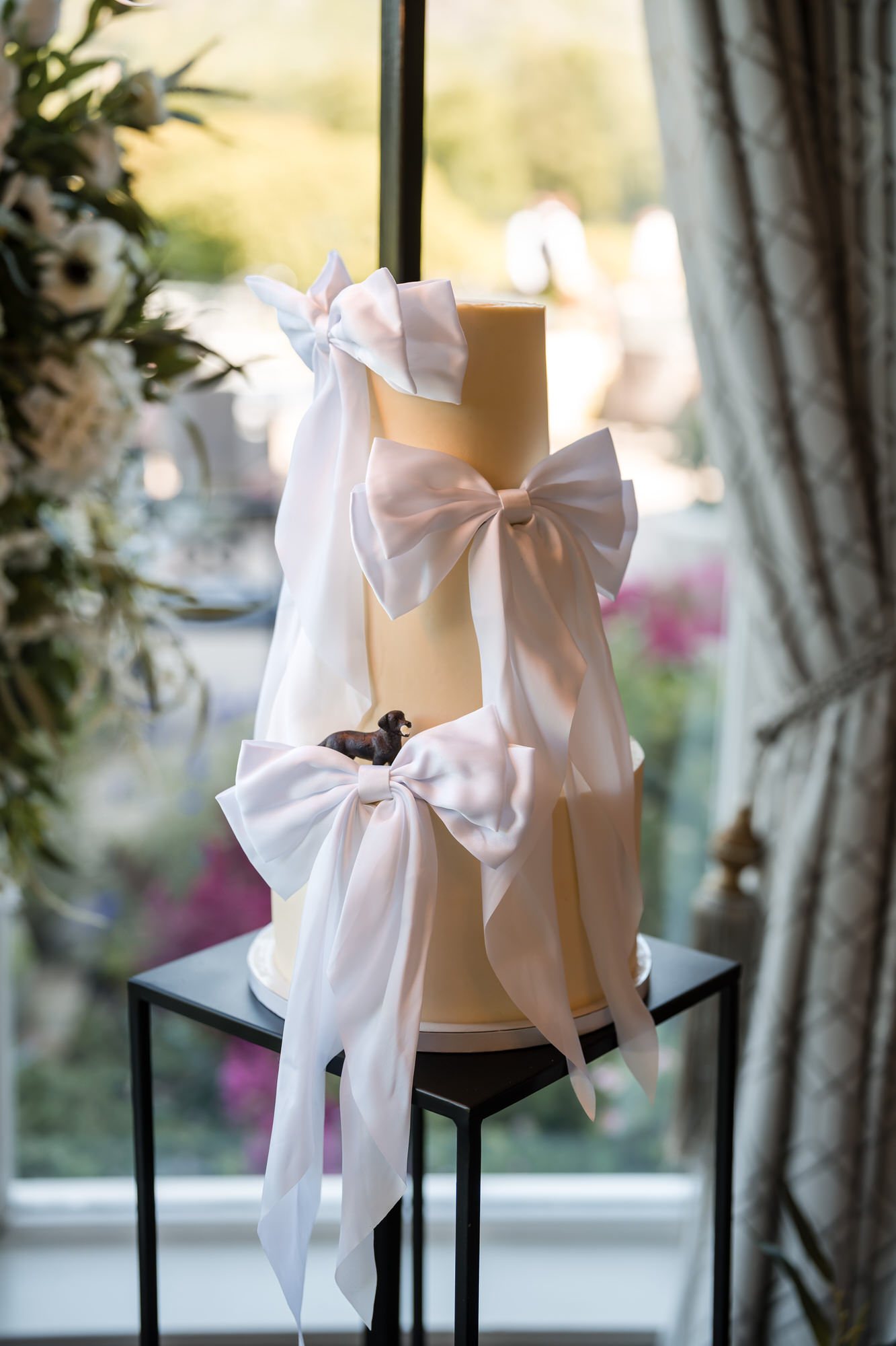 Dan and Amy's three-tier wedding cake decorated with white bows and a small dog figure