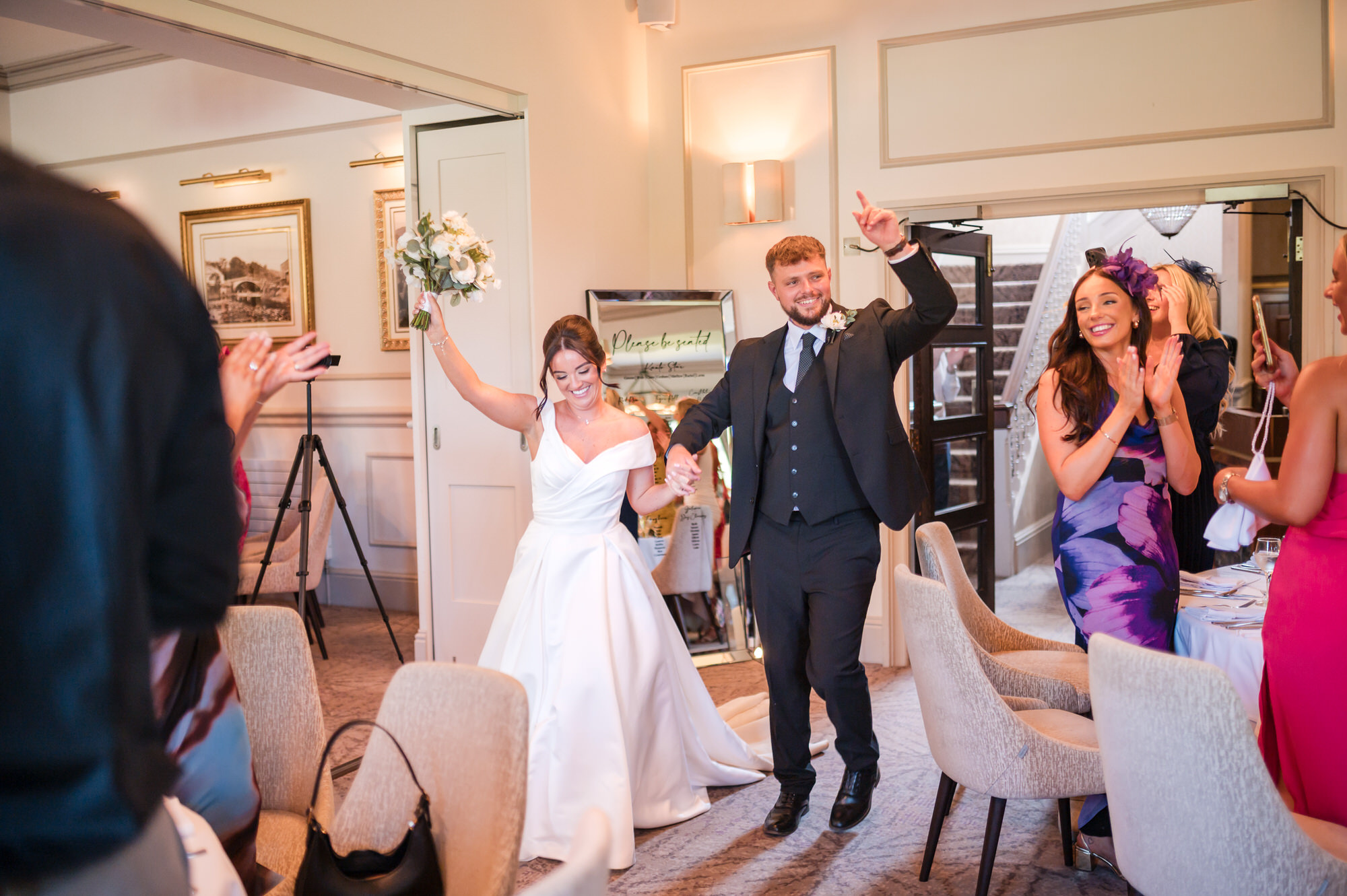 Dan and Amy walking between applauding guests at the wedding breakfast