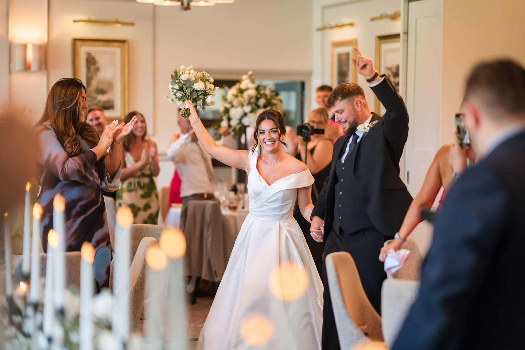 Amy raising her bouquet as she and Dan enter the reception room