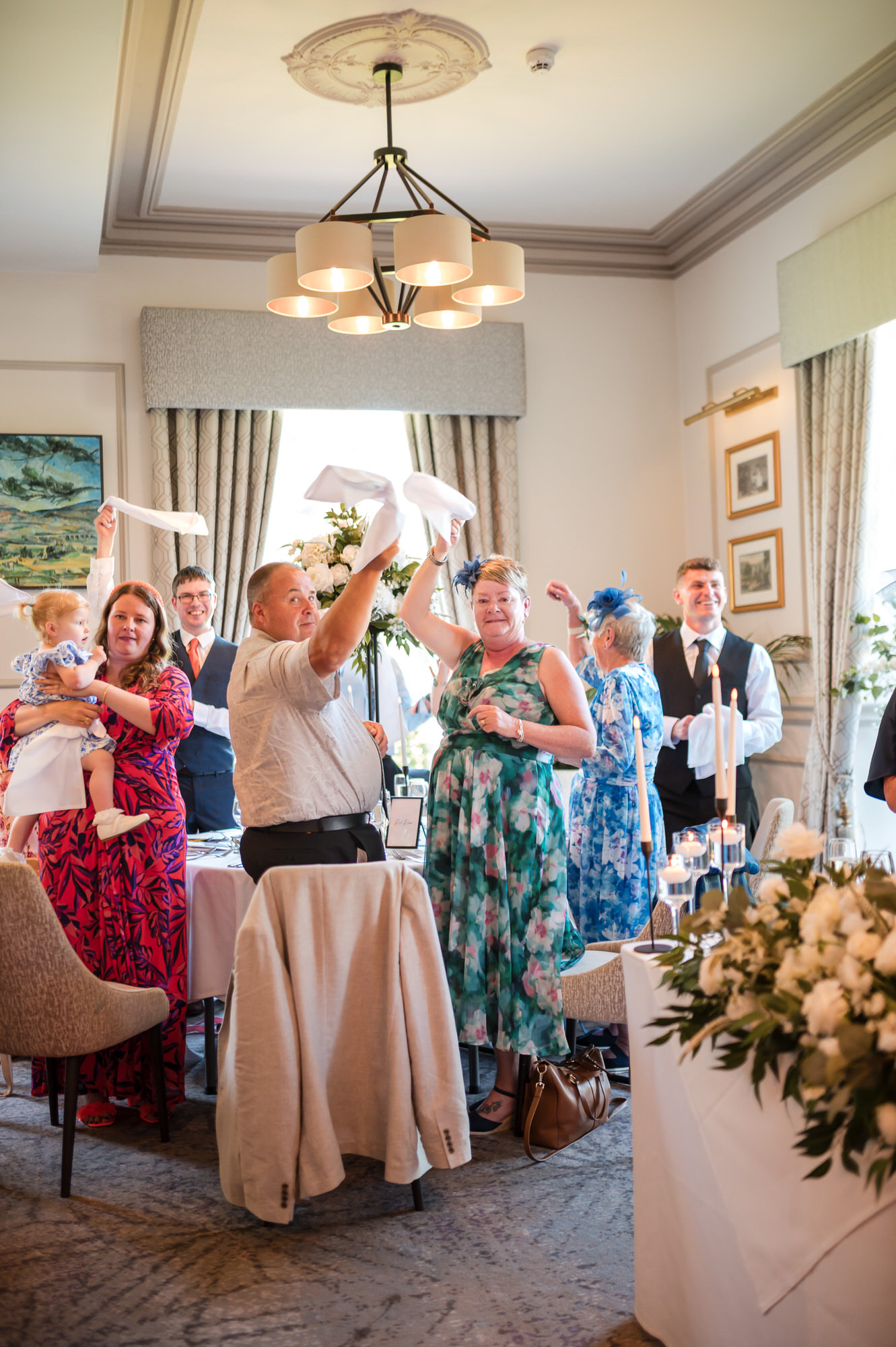 Wedding guests waving napkins and cheering Dan and Amy's entrance