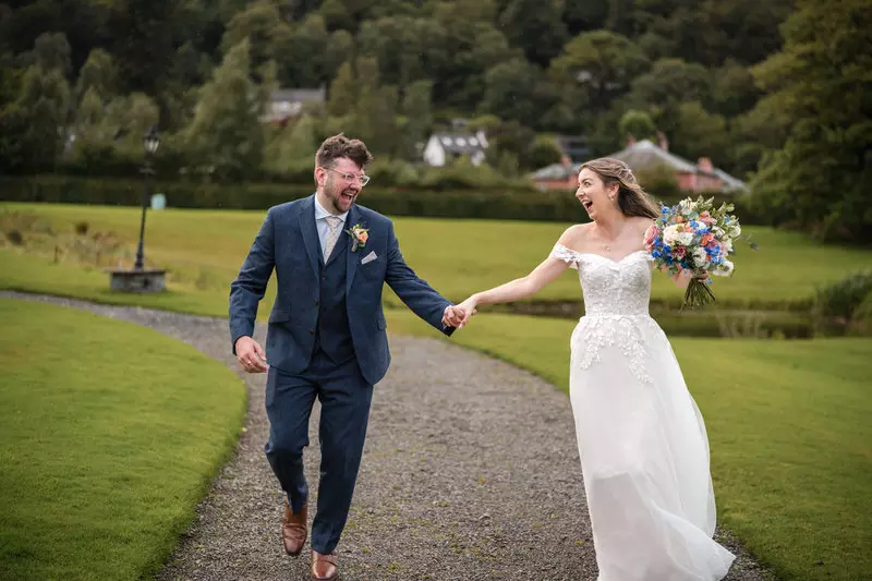 Bride and groom running and laughing just married at Inn on the Lake in the Lake District