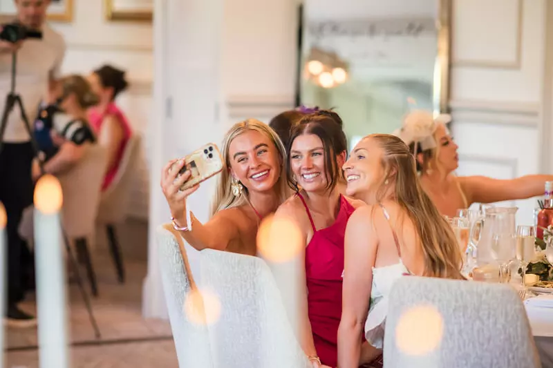 Inn on the Lake wedding reception guests laughing selfie moment Wedding guests laughing together while taking a selfie during a reception at Inn on the Lake in Cumbria