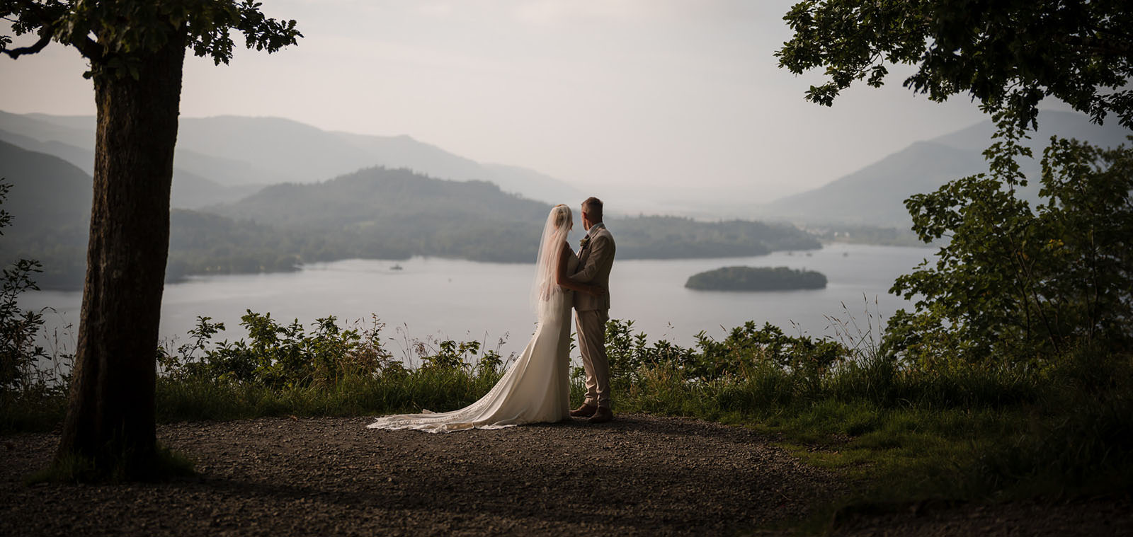 Lake District wedding landscape portrait Silhouette wedding couple beneath trees overlooking a Lake District lake and distant hills