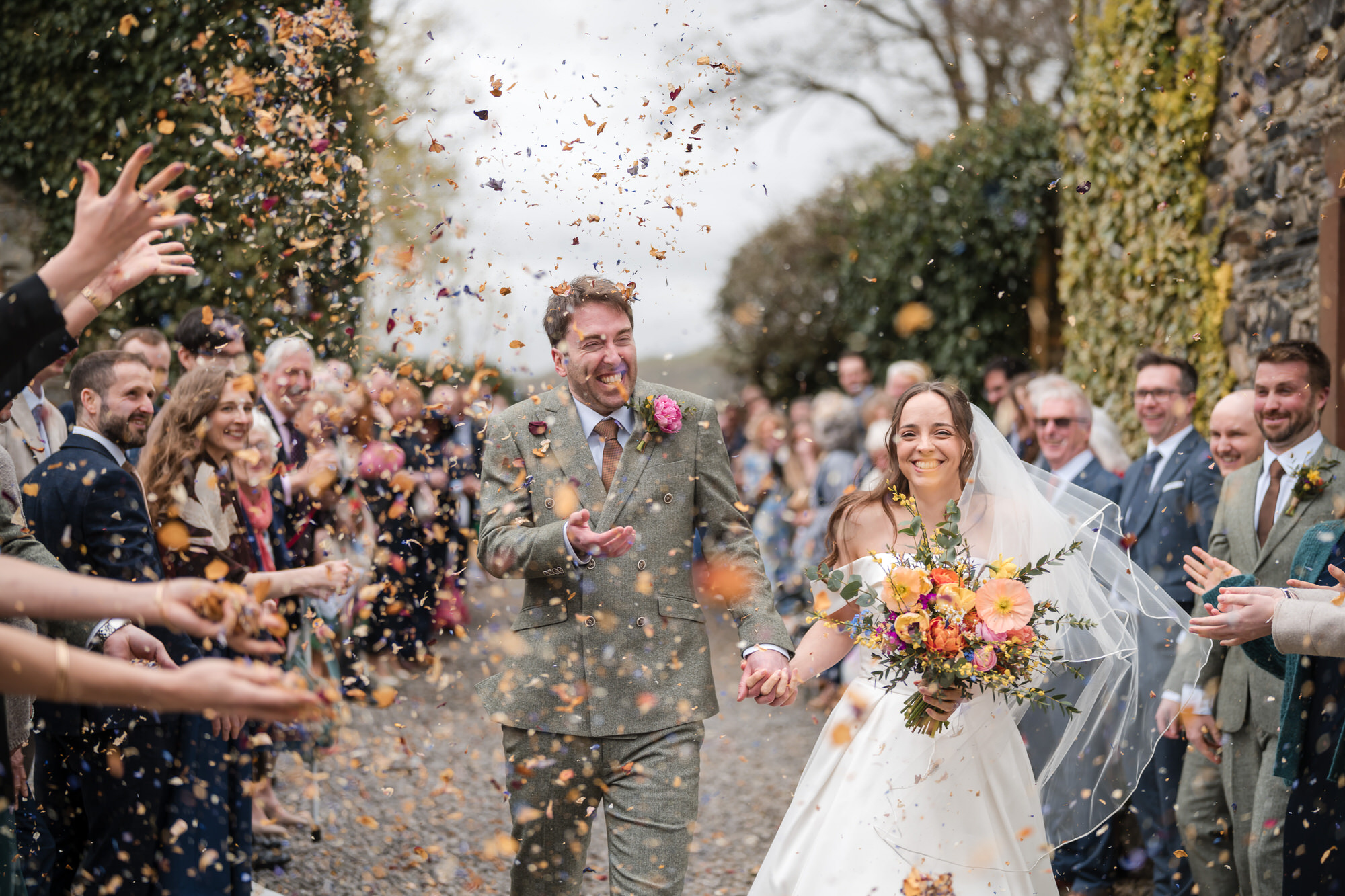 Wedding couple walking through confetti at Low Hall The Lakes