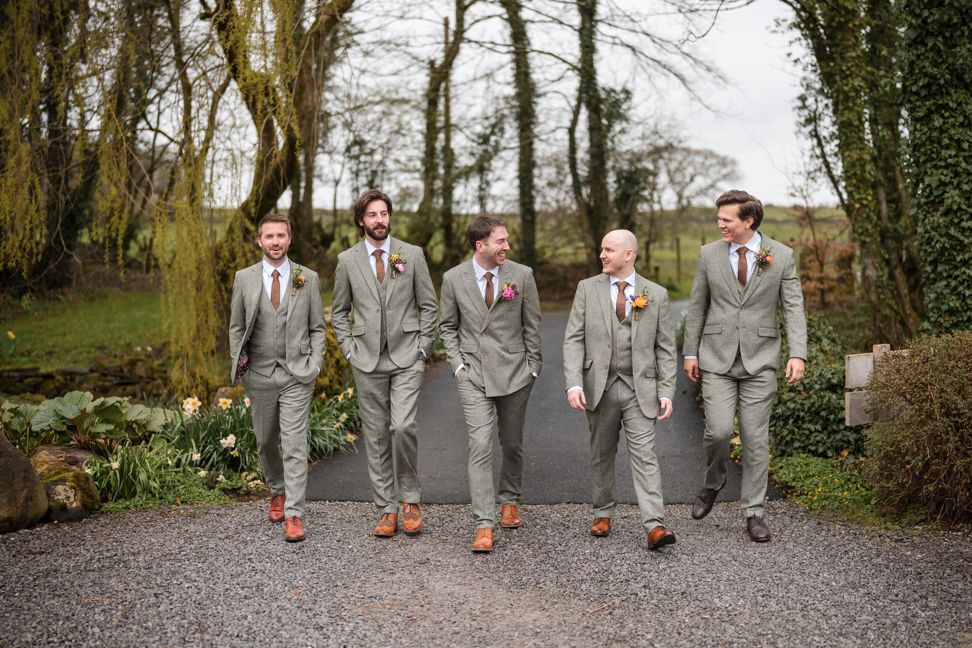 Groomsmen walking through the grounds at Low Hall The Lakes wedding venue