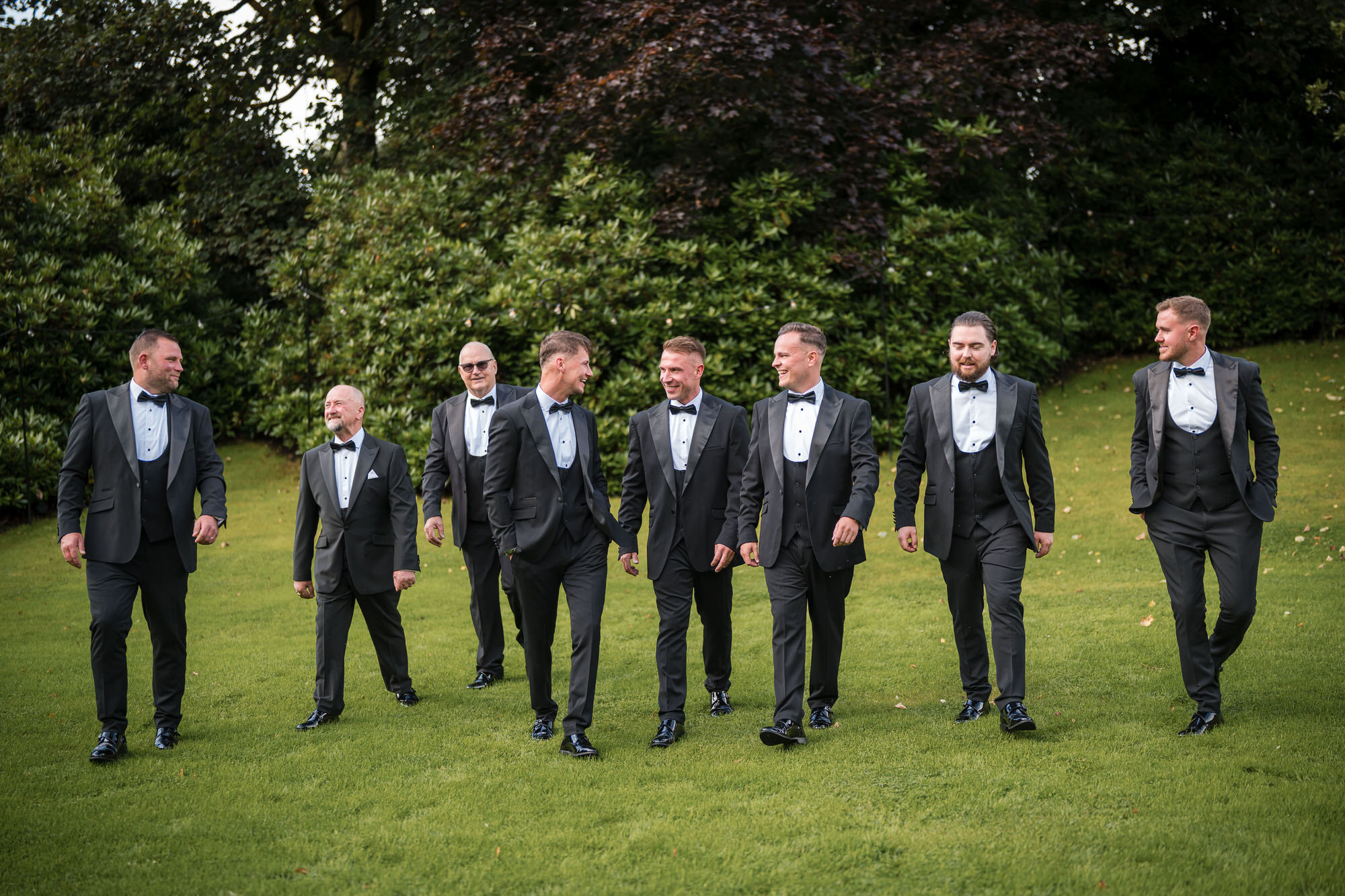 Dan and his groomsmen walking across the lawn in black tie