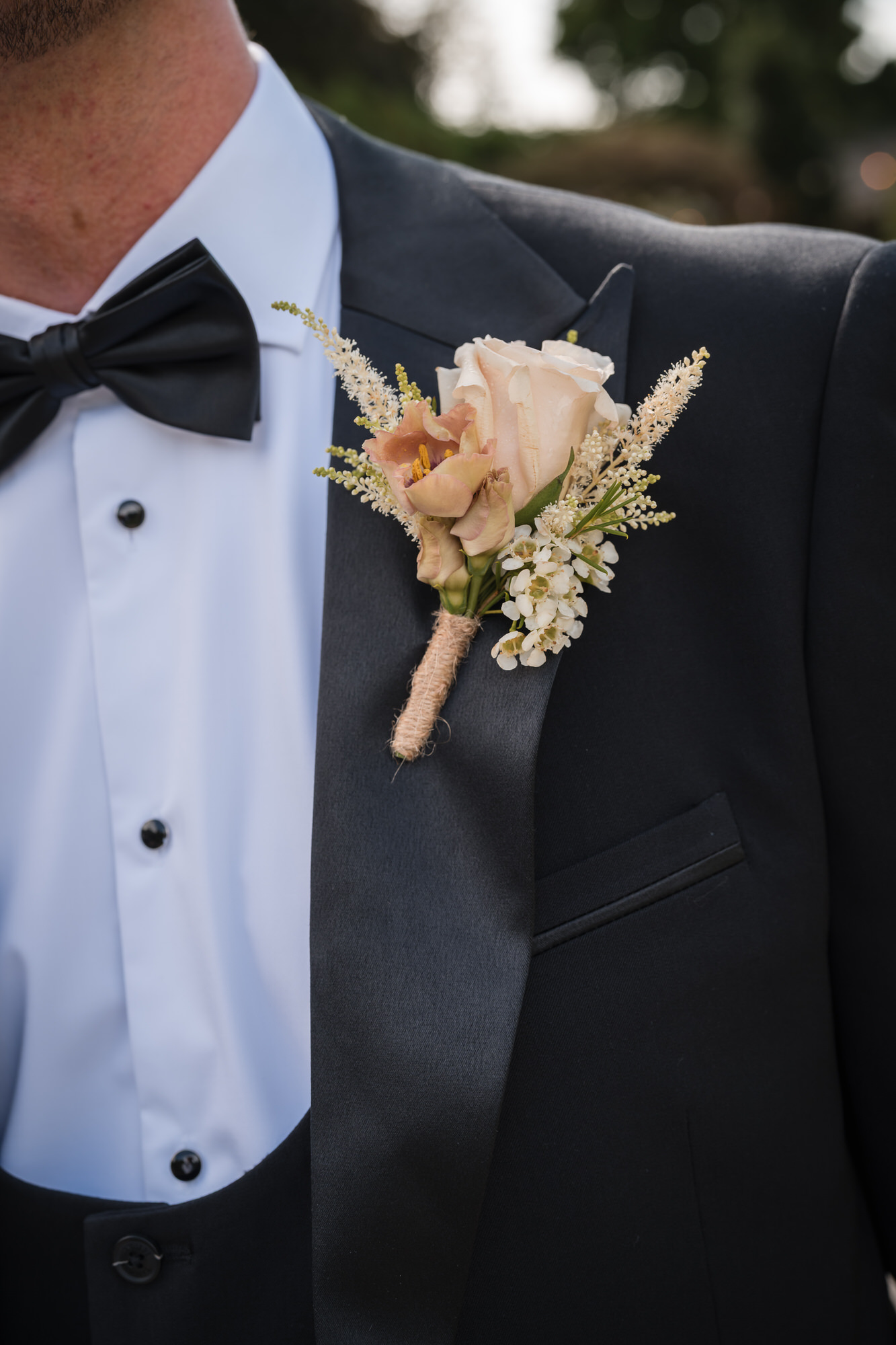 Black bow tie, tuxedo and pale floral buttonhole from the wedding morning