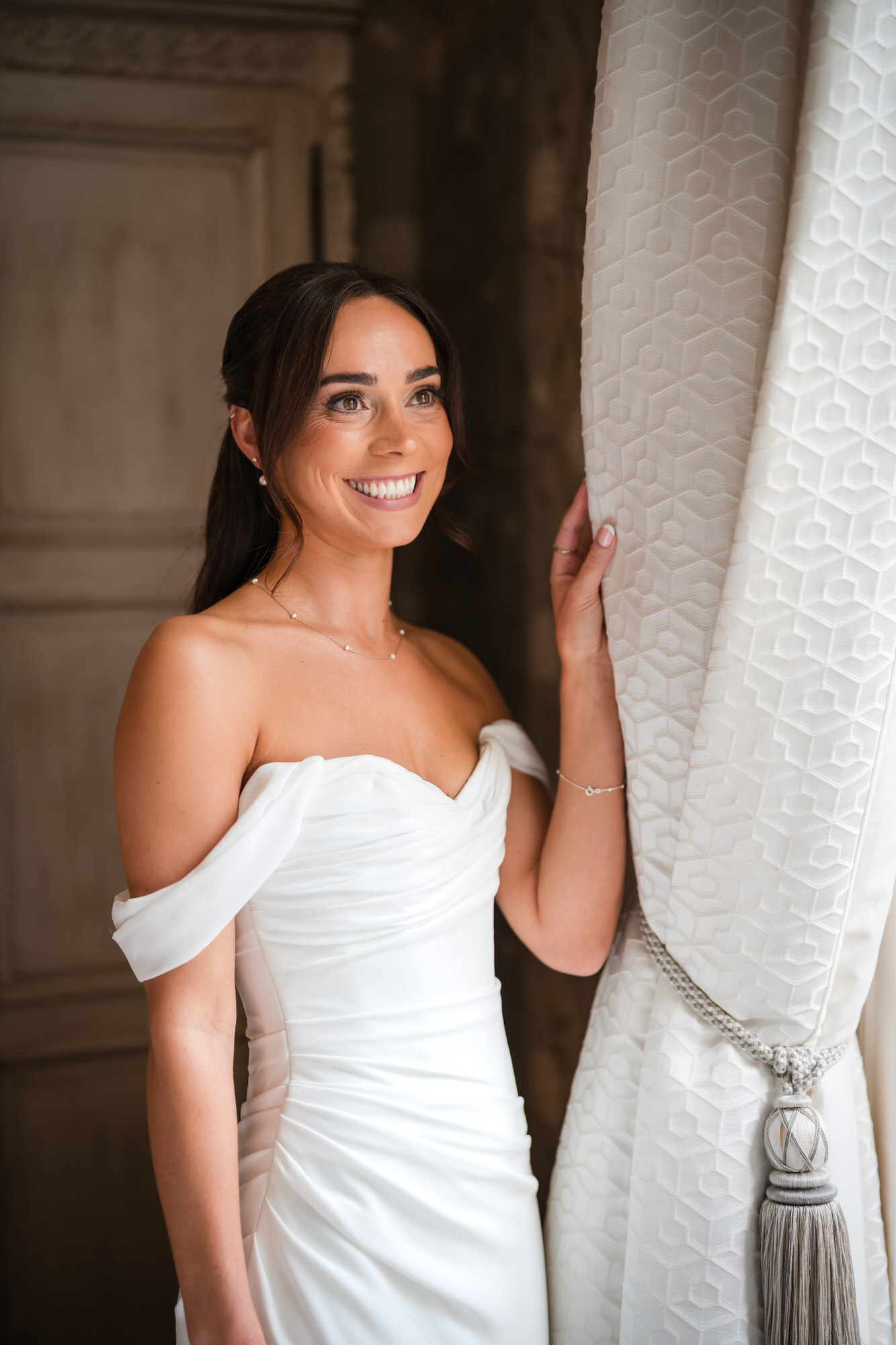 Ellie smiling beside the curtains during her bridal preparations