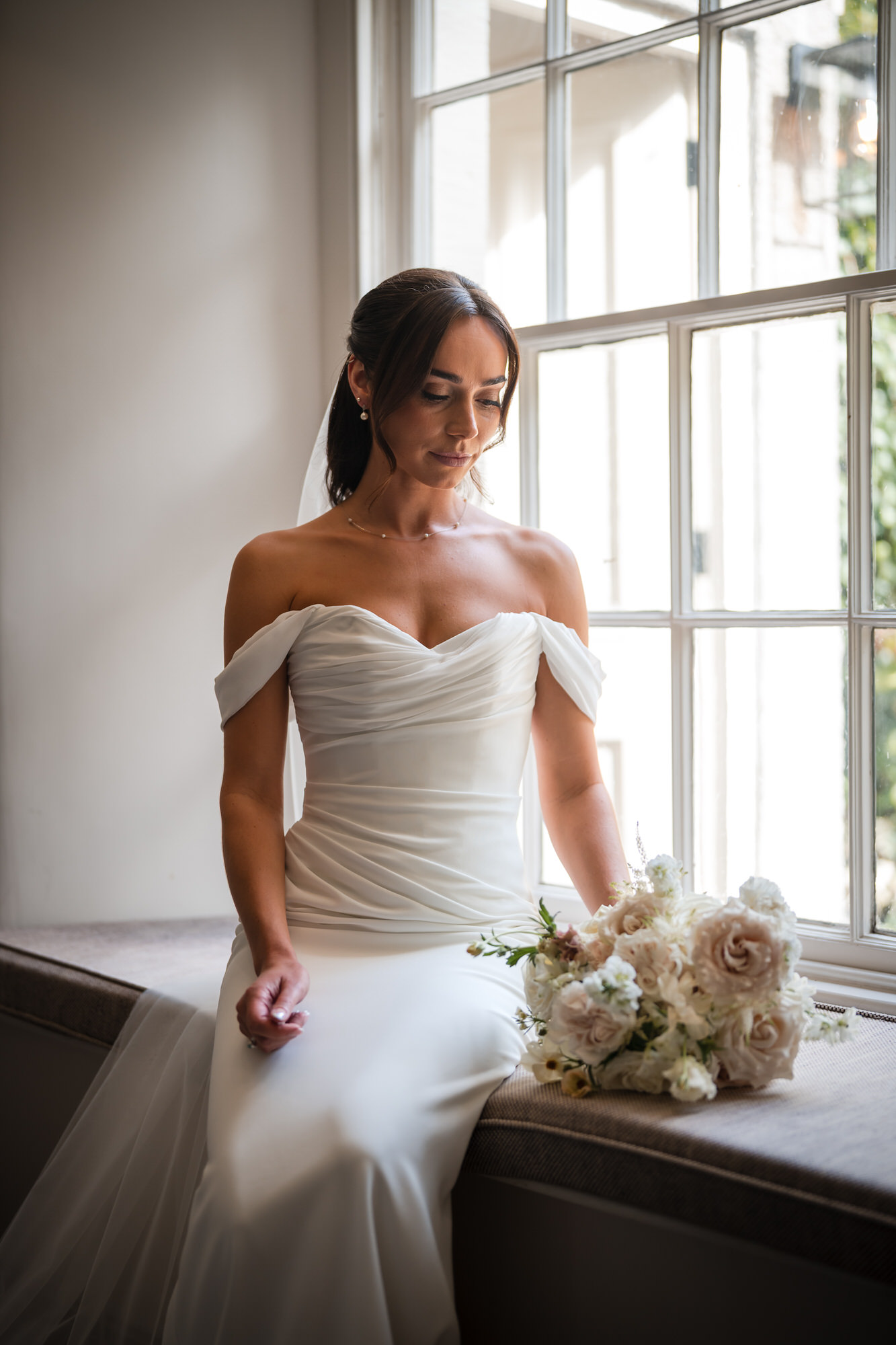 Ellie standing beside the window with her wedding bouquet