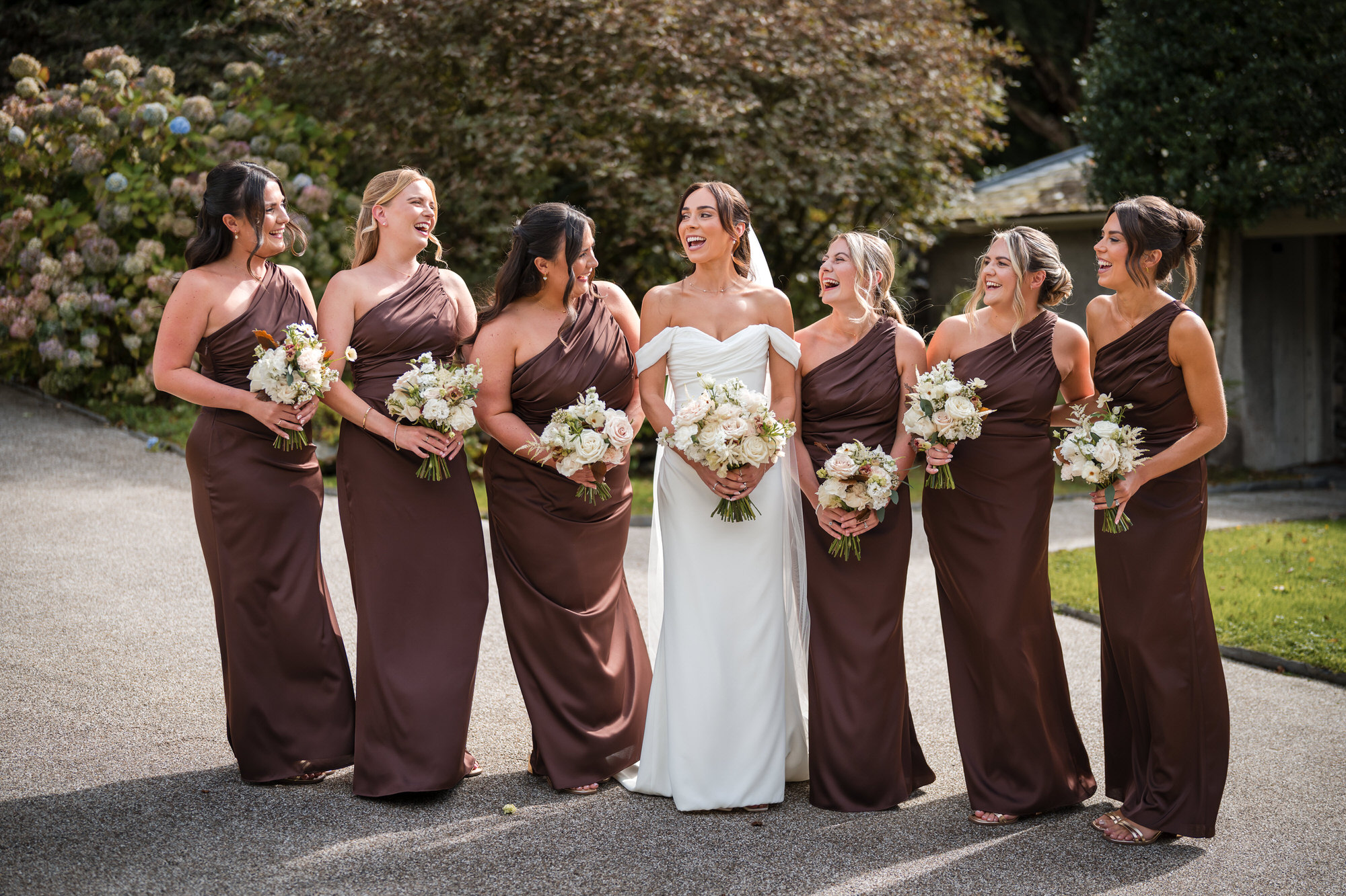 Ellie laughing with her bridesmaids in chocolate-brown dresses