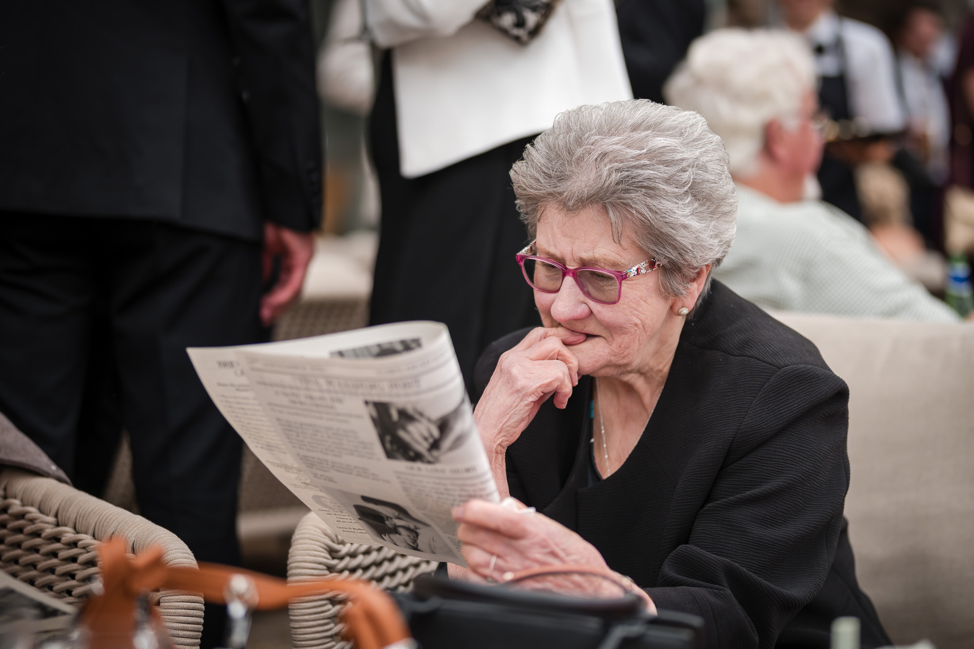 A wedding guest reading Dan and Ellie’s personalised wedding newspaper