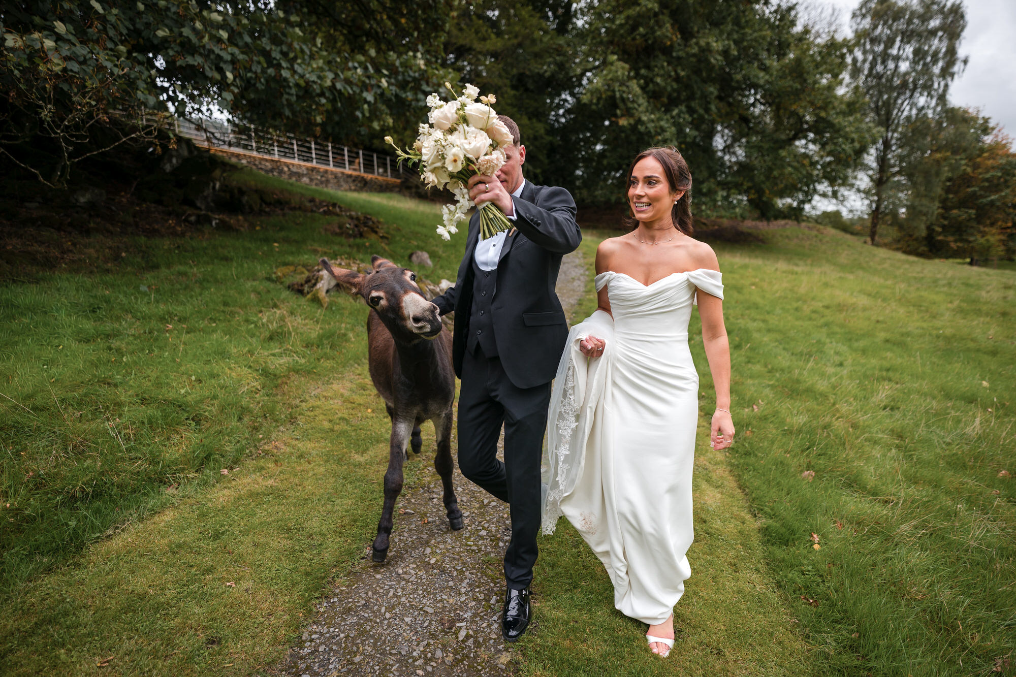Dan holding Ellie’s bouquet out of reach as Eddie the donkey joins their walk