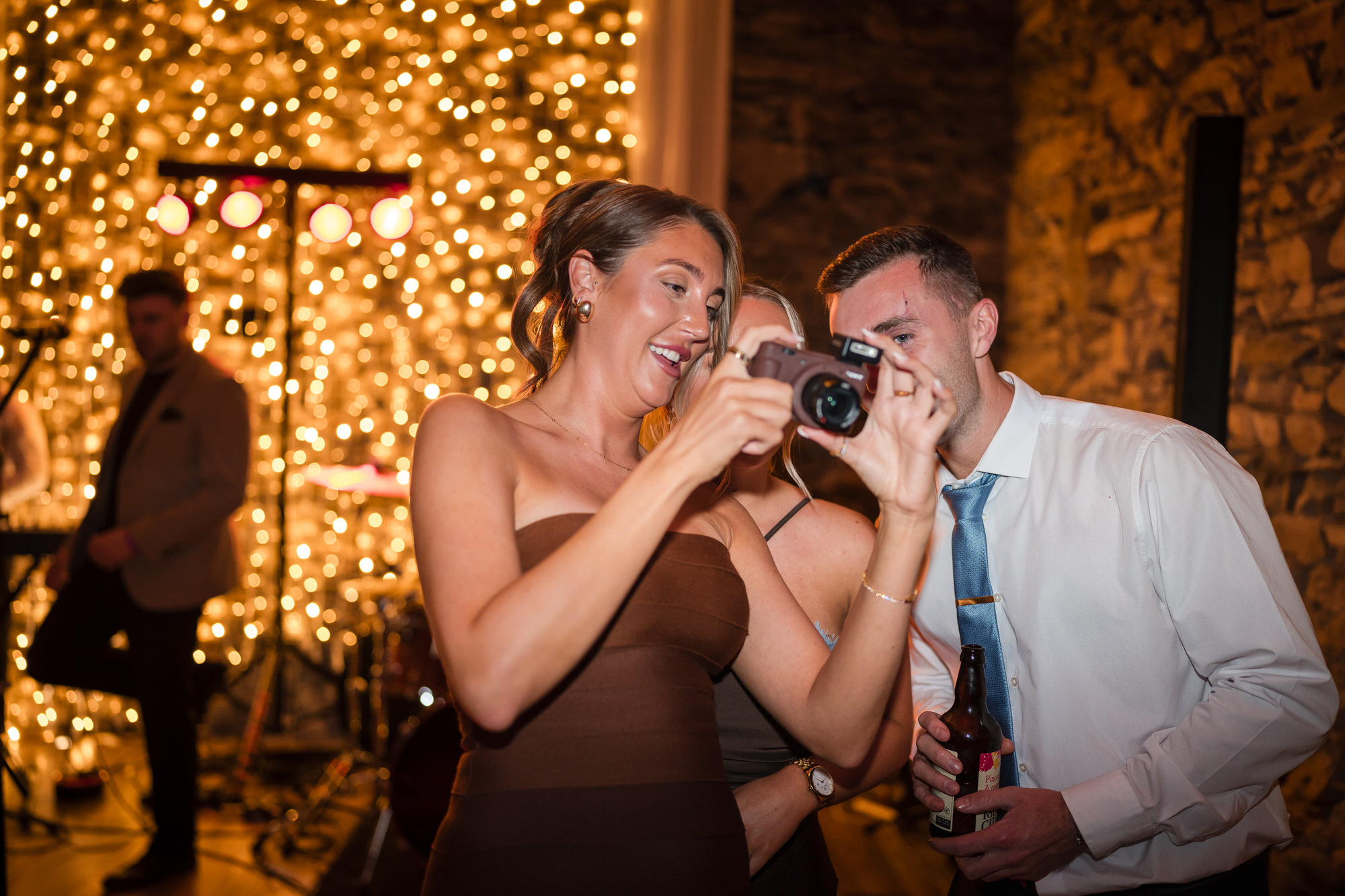 A bridesmaid and guest enjoying a candid moment with a camera