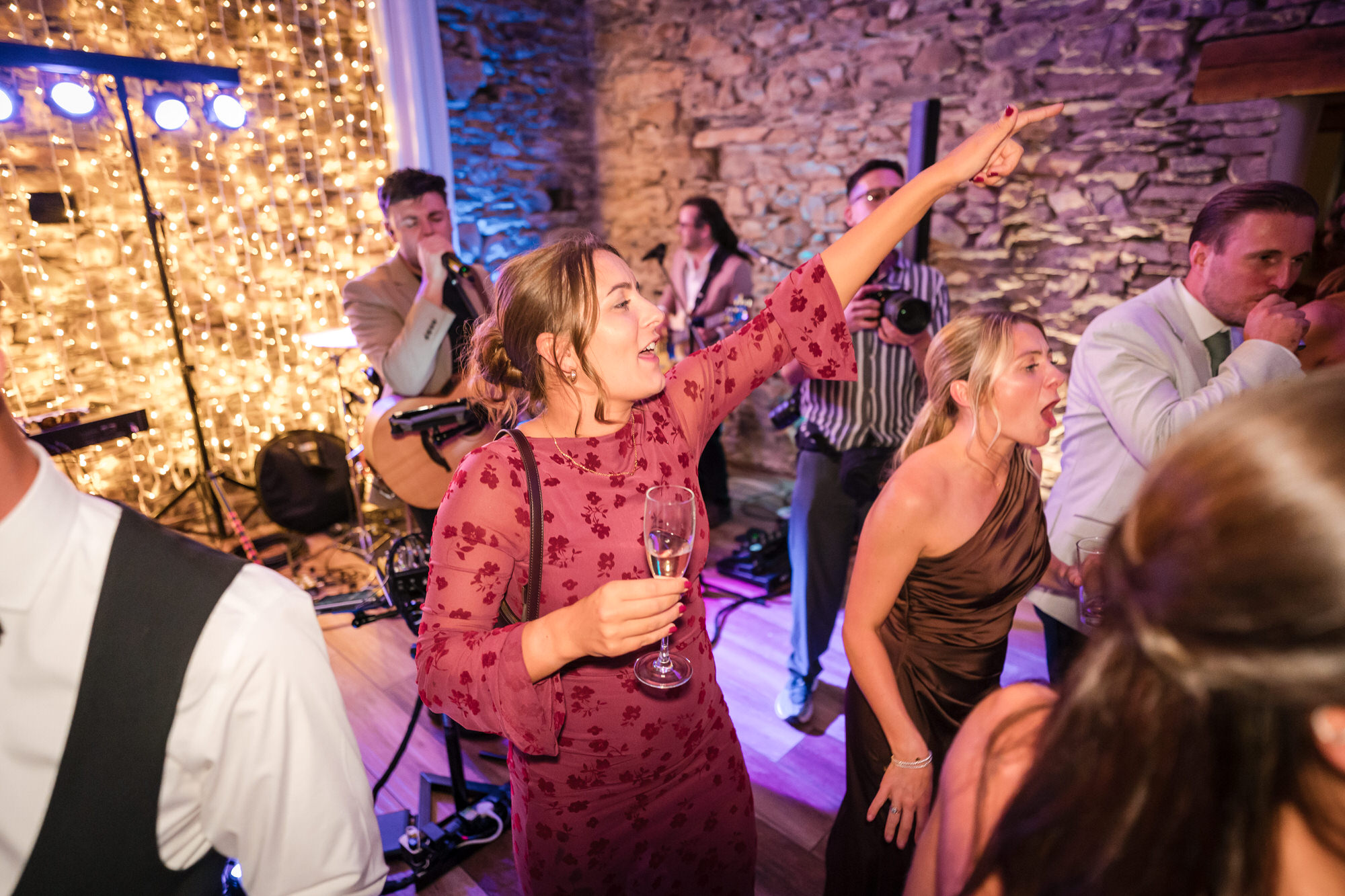Wedding guests joining the party beneath the warm barn lights